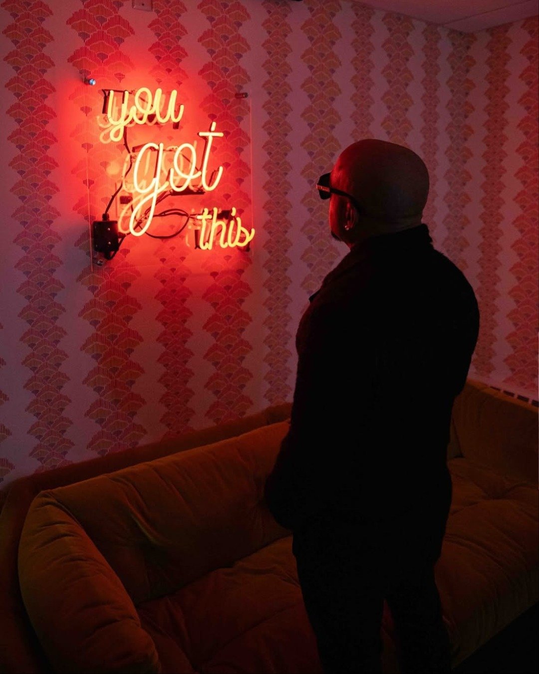 a man standing in front of a neon sign that says you'rejod