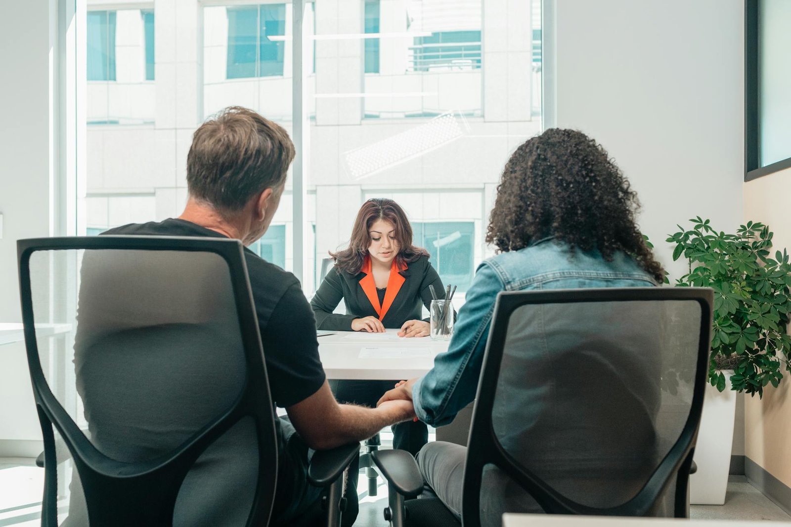 a woman in a business suit sitting at a table with a couple needing business consulting assistance